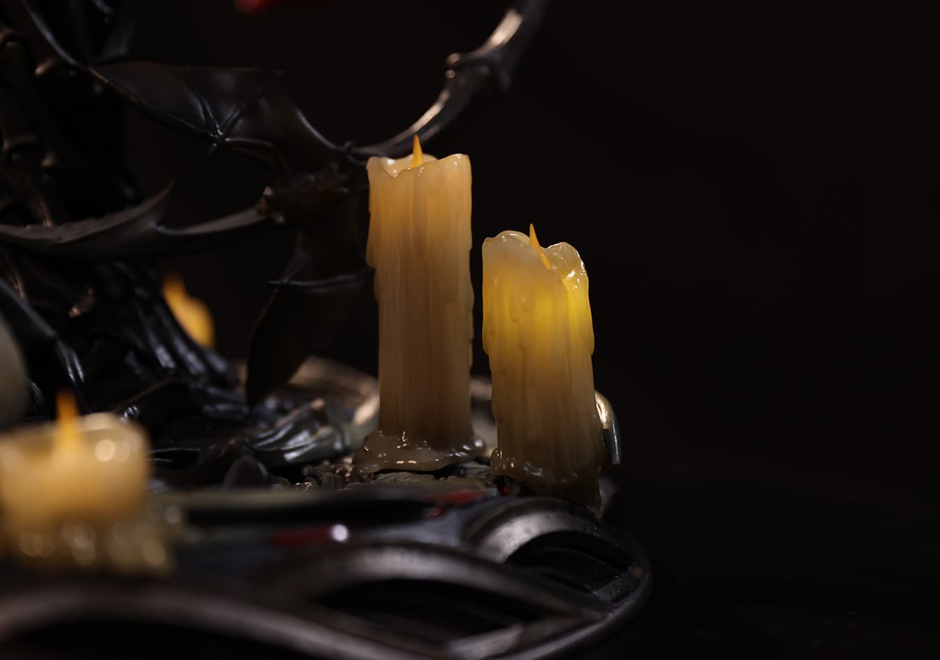 Close-up detail of the candles with a realistic melted wax effect on the base of the Morrigan statue.